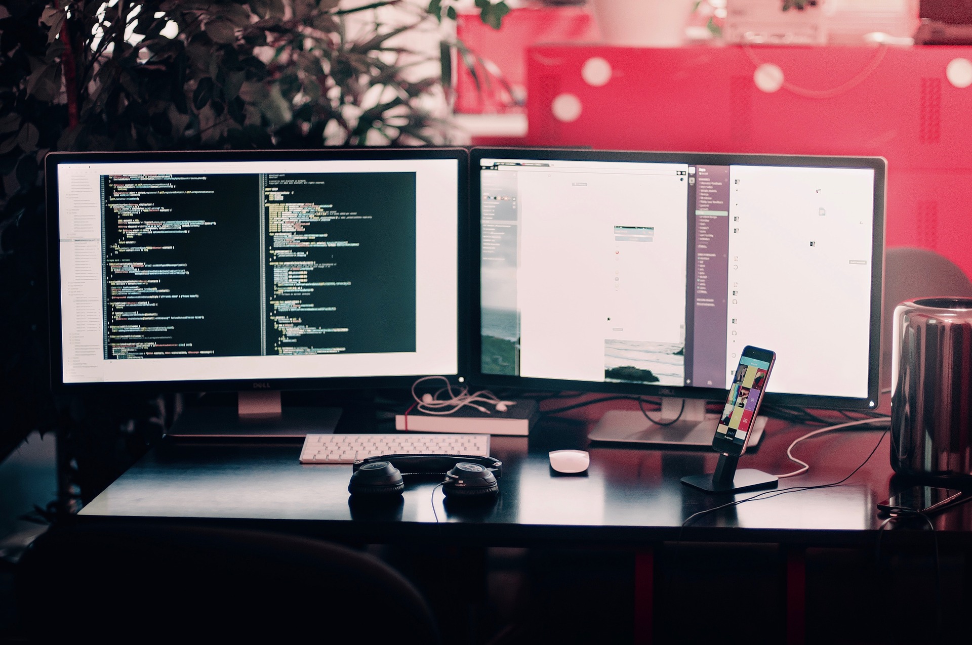 A photograph of two computer monitors on a desk displaying lines of code.